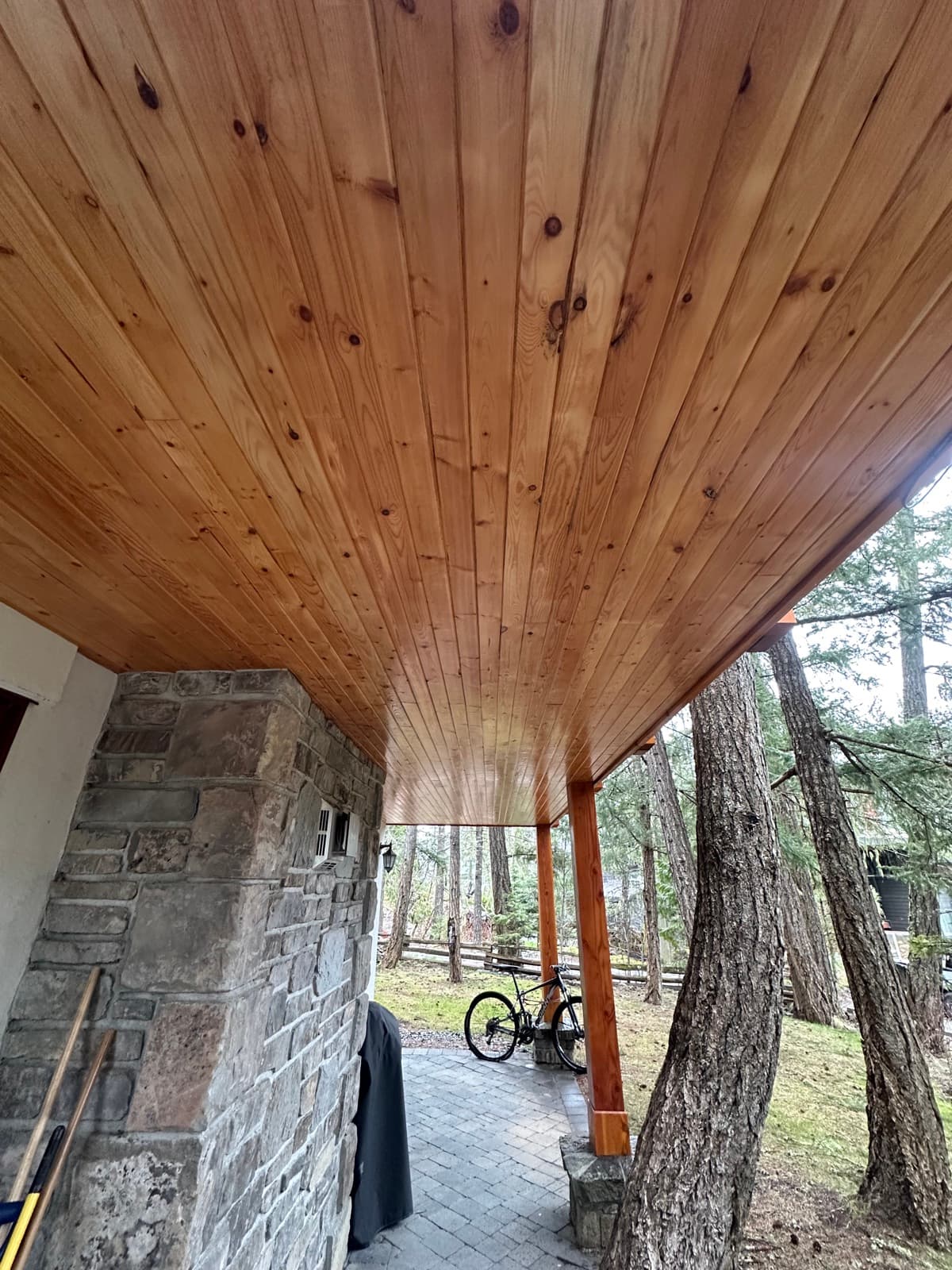 Close view of clear-coated knotty pine tongue-and-groove entry wall and soffit with timber beams
