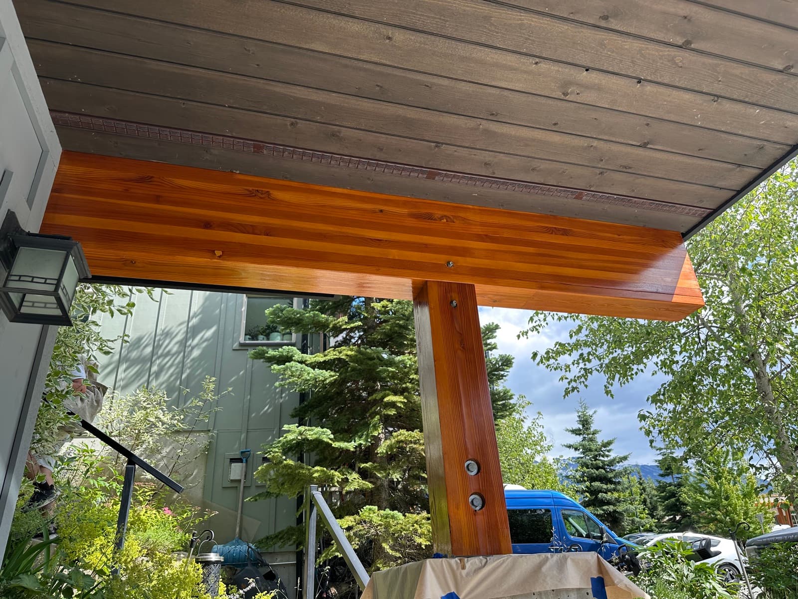 Upward view of a freshly stained glossy orange-toned fir glulam beam and post on a modern entry canopy