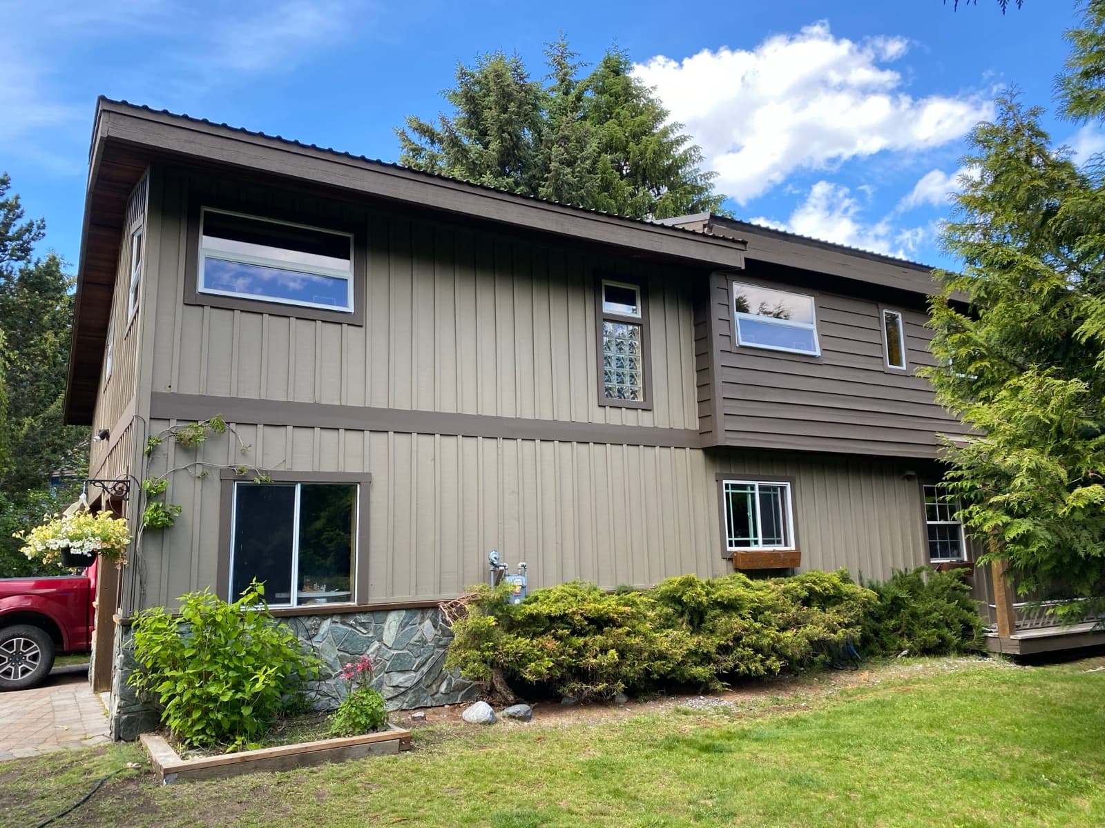 Freshly repainted two-storey home with two-tone taupe board-and-batten siding, crisp dark brown trim